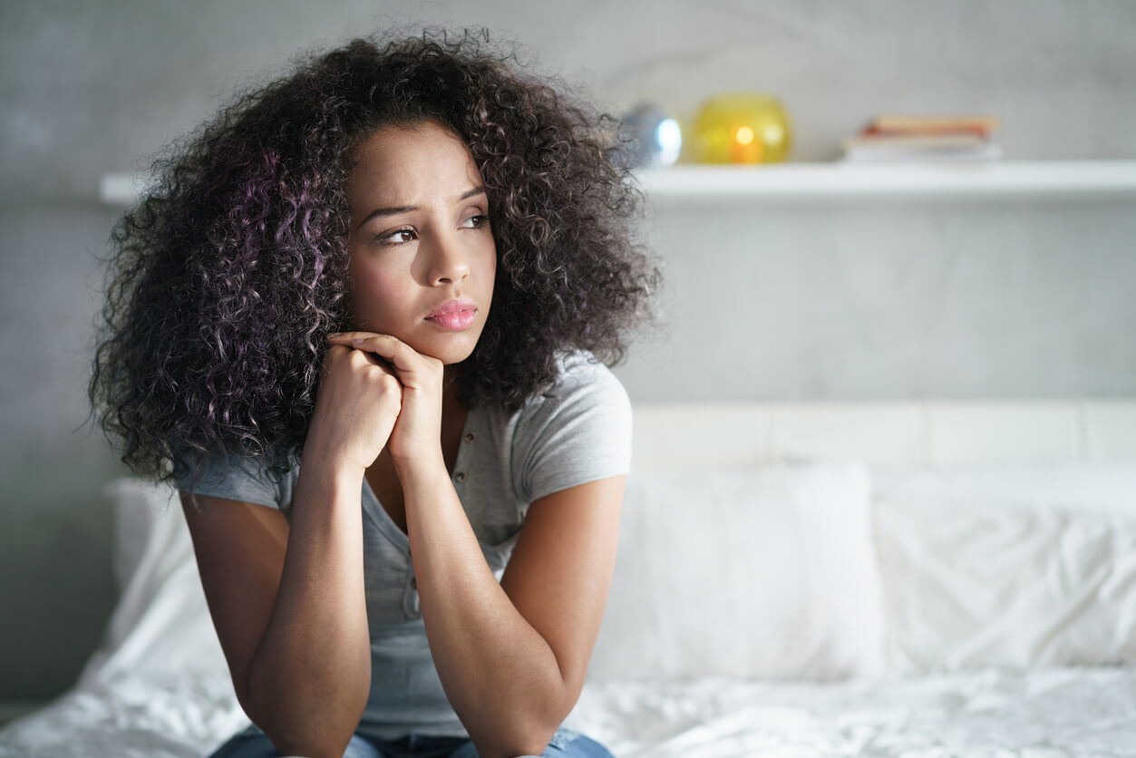 Woman with curly hair sitting on the bed